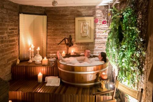 a man and woman in a bath tub with candles at La vanguardia by Don Ramon Hotel Boutique & Spa in Canela
