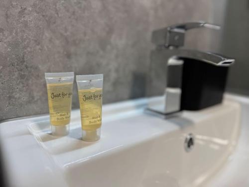 two cups sitting on a bathroom sink with a faucet at Central 1BR Apt with Parking in Auchterarder