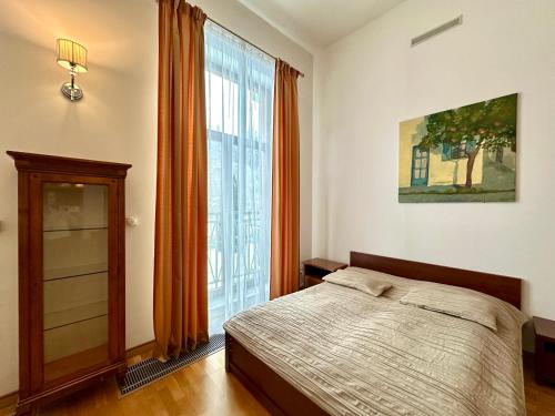 a bedroom with a bed and a large window at Slunecni Lazne Apartments in Karlovy Vary