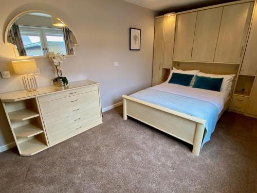 a bedroom with a bed and a dresser and a mirror at Kirkwall town centre apartment 3 in Kirkwall