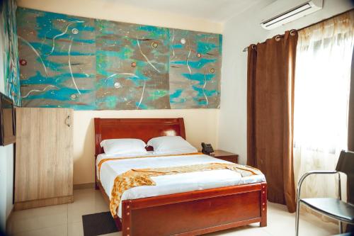 a bedroom with a bed with a painting on the wall at Guest House Lumen in Lomé