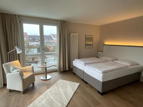 a bedroom with a bed and a chair and a large window at pepb Schulungshotel in Sarstedt