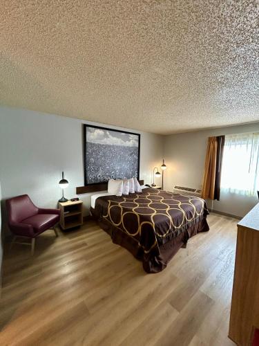 a hotel room with a bed and a chair at Super 8 by Wyndham Sterling CO in Sterling
