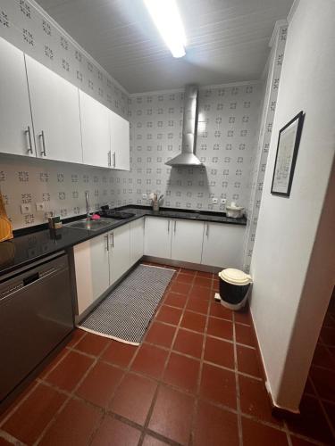 a kitchen with white cabinets and a red tile floor at Casa do Alto da Torre in Abrantes