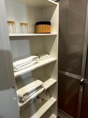 a closet with white shelves and towels and a refrigerator at Casa do Alto da Torre in Abrantes