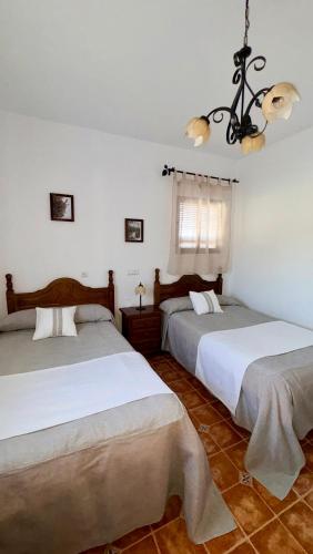 two beds in a room with white walls at Casa Rural Cortijo Cerro Limon in Málaga