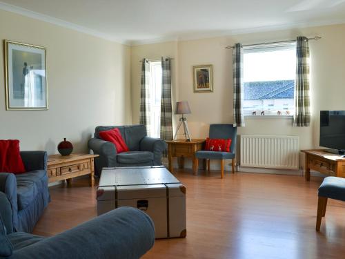a living room with couches and chairs and a tv at Ness-Side Apartment in Inverness
