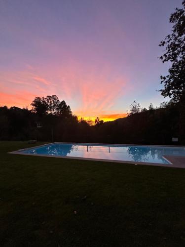 a sunset over a swimming pool in a yard at Ri&Vale Alojamentos in Vieira do Minho