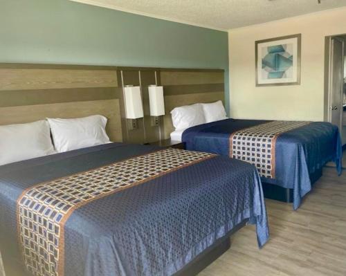 a hotel room with two beds with blue sheets at Executive Inn & Suites in Beaumont