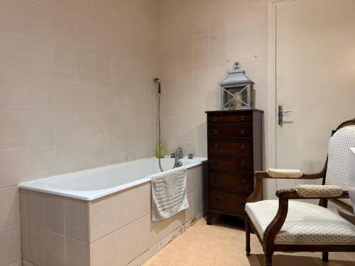 Un baño con bañera, silla y tocador. en L Epernon, en Alençon