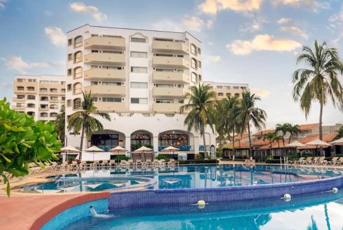 a hotel with a swimming pool in front of a building at Villa 1 en Hotel Tesoro Ixtapa in Ixtapa