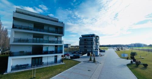 a tall building next to a street with a parking lot at SERENITAS Apartment RIVA PARK in Dunajská Streda
