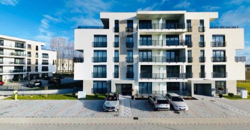 a white building with cars parked in front of it at SERENITAS Apartment RIVA PARK in Dunajská Streda