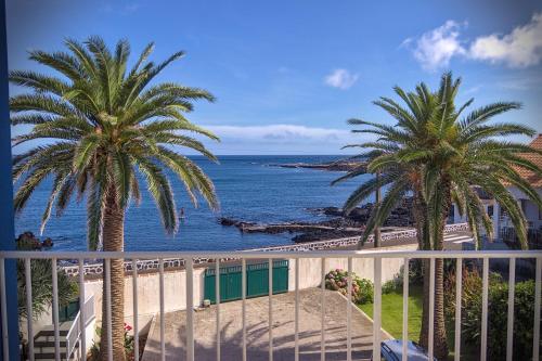 a view of the ocean from a balcony with palm trees at Porto Martins Bay Apartments (AL) in Porto Martins