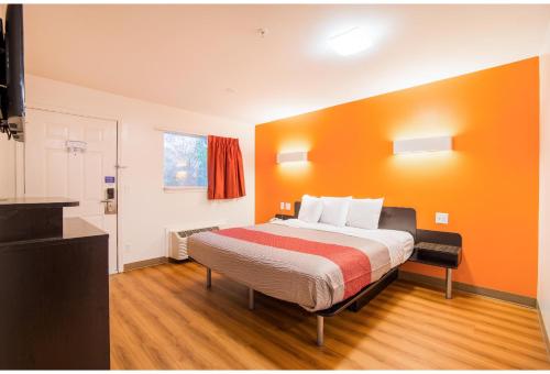 a bedroom with a bed with an orange wall at Studio 6 Extended Stay - Augusta, GA - Fort Gordon in Augusta