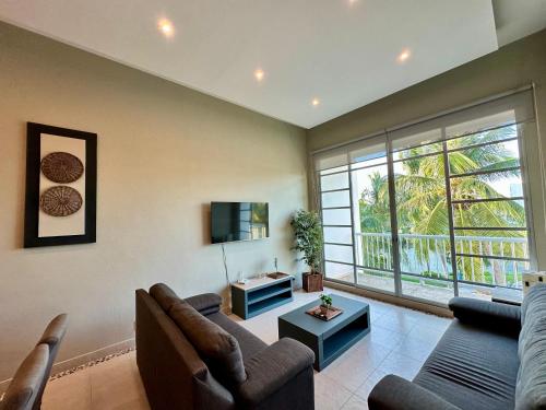 a living room with a couch and a tv at Casa del Sol Lujoso Departamento en Acapulco in Acapulco