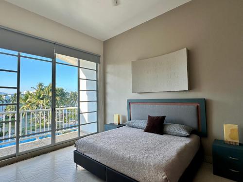 a bedroom with a bed and a large window at Casa del Sol Lujoso Departamento en Acapulco in Acapulco