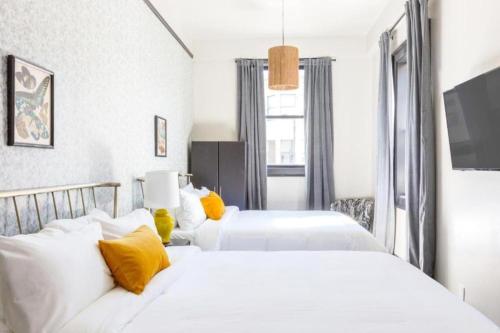 two white beds in a bedroom with yellow pillows at Inn at Gough in San Francisco