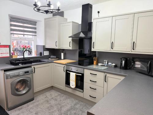 a kitchen with white cabinets and a washing machine at 18 Main Street in St Bees