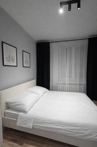 a white bed in a bedroom with a window at Apartament Centrum in Płock