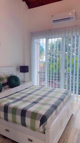 a bedroom with a large bed with a large window at Villa Auxesiaa in Wattala