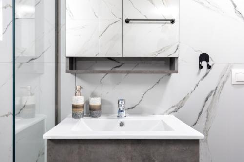 a white bathroom with a sink and a mirror at Anatoli Urban Apartment with private parking in Xanthi