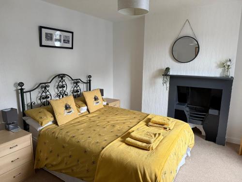 a bedroom with a bed with yellow sheets and a fireplace at 16 Main Street in St Bees