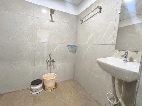 a white bathroom with a sink and a shower at Hotel Visara Grand in Gokarna