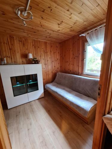 a couch in a small room with a window at Domek nad jeziorem Anastazewo in Anastazewo