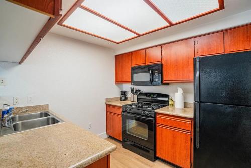 a kitchen with wooden cabinets and a black refrigerator at Resort-Style 3RB-2BR-1BR Retreat, Pool, Gym, Parking in Tempe
