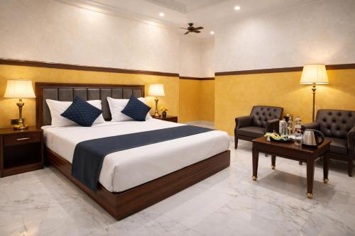 a bedroom with a bed and two chairs and a table at Hotel Hare Krishna & Banquet, Vrindavan in Vrindāvan