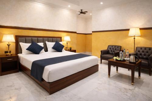a bedroom with a bed and two chairs and a table at Hotel Hare Krishna & Banquet, Vrindavan in Vrindāvan