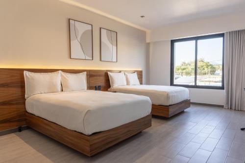 ein Hotelzimmer mit zwei Betten und einem Fenster in der Unterkunft MARUVA Hotel Ejecutivo in Tecomán