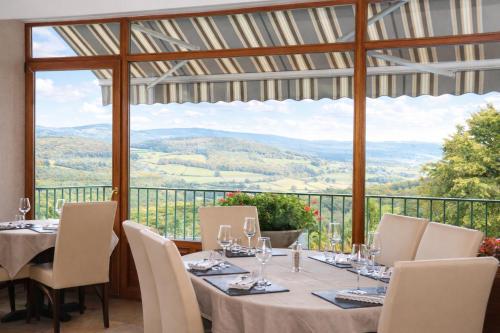 a dining room with a table and chairs and a large window at Logis Hôtel-Restaurant Au Vieux Morvan, au cœur de la Bourgogne, Piscine & Spa, Hôtel Climatisé in Château-Chinon