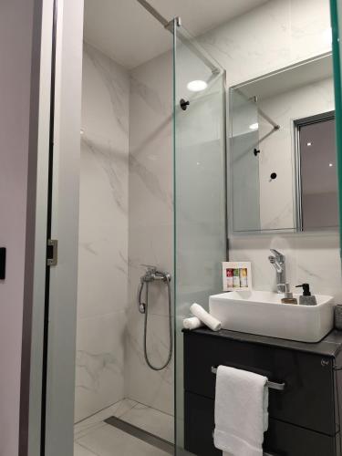 a bathroom with a sink and a glass shower at Corfu Nature Suites in Corfu