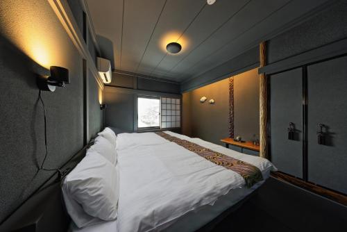 a large bed in a small room with a window at NINE plus River with Private Sauna Stay in Kanazawa