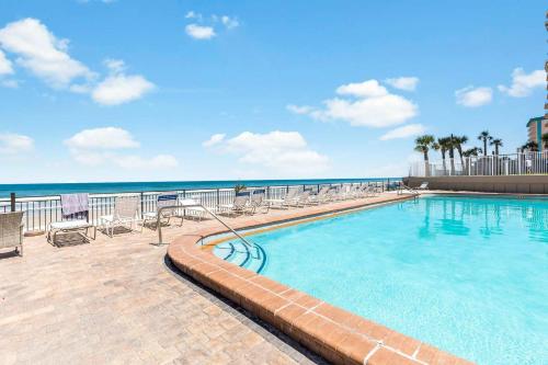 a swimming pool with chairs and the ocean in the background at Beach Studio with Partial Water Views Sundeck Pool in Daytona Beach