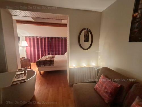 a living room with a couch and a bed with a mirror at Gîte Du Côté de Chez Souesmes in Souesmes