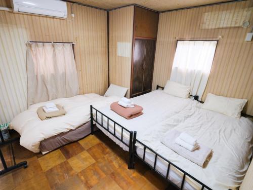 two beds in a room with white sheets and towels at Hikari-Private House in Tokyo