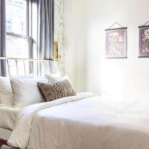 a bedroom with a bed with white sheets and a window at Inn at Gough in San Francisco