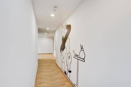 a hallway with a white wall with drawings on it at Hotel O Crowninn in Faridabad
