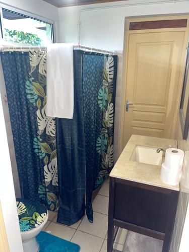 a bathroom with a shower curtain and a sink at Atea Fare Pāmata'i in Faaa