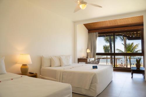 a bedroom with two beds and a view of the ocean at Arraial D'ajuda Eco Resort in Arraial d'Ajuda