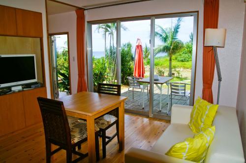 a living room with a couch and a table and a television at Beach Village Nosoko in Ishigaki Island