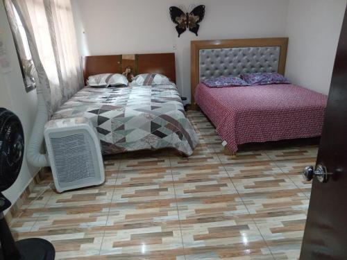 a bedroom with two beds and a parquet floor at Casa Turistica Andy in Cali