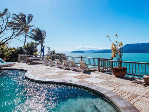 a swimming pool with benches and the water at Vilatoro Guest House in Ilhabela