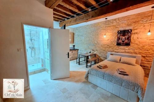 a bedroom with a bed and a brick wall at Le Petit Cocon Cozy studio proche de Lyon in Couzon-au-Mont-dʼOr
