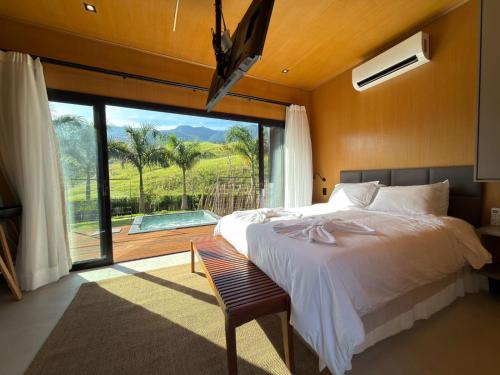 a bedroom with a large bed and a large window at Villa Mantiqueira SFX - Cabanas in São Francisco Xavier