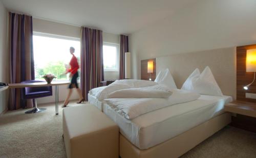 ein Hotelzimmer mit einem Bett und einer Person, die durch ein Fenster geht in der Unterkunft Cityhotel D&C St.Pölten in Sankt Pölten