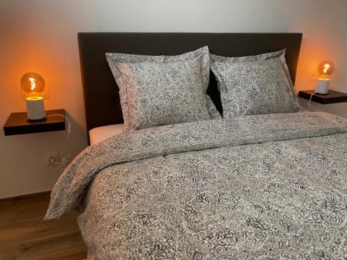 a bedroom with a bed with pillows and two lamps at Tiny House Ô Secret du Wérihay in Spa